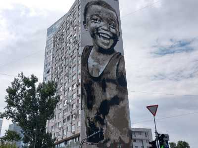 Недалеко от метро Дворец Украины, на улице Казимира Малевича, на стене дома, расположен огромный мурал с изображением чернокожего мальчика расплывшегося в беззаботной улыбке. 